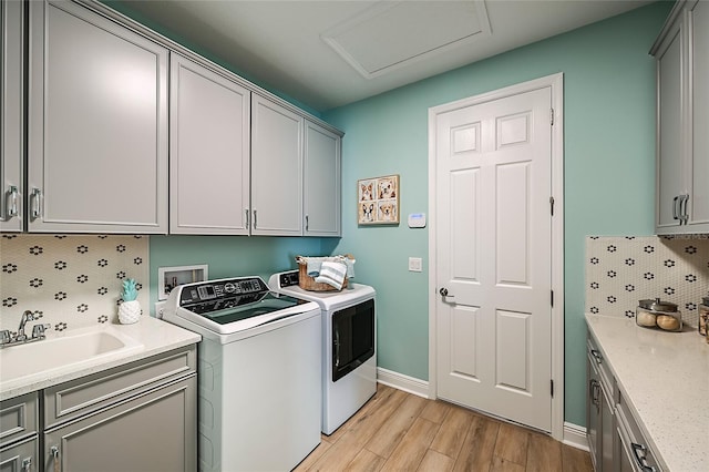 laundry room with cabinet space, attic access, baseboards, washer and dryer, and light wood-style floors