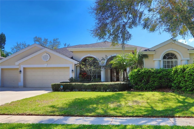 view of front facade with concrete driveway, stucco siding, an attached garage, and a front yard