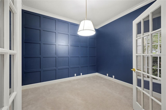 empty room with carpet, baseboards, a decorative wall, and crown molding