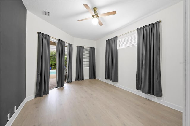 unfurnished room featuring a ceiling fan, baseboards, visible vents, and light wood finished floors