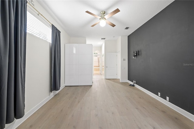 spare room featuring visible vents, a ceiling fan, light wood-style flooring, and baseboards