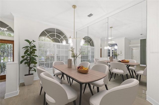 dining space with crown molding, visible vents, a chandelier, light wood-type flooring, and baseboards