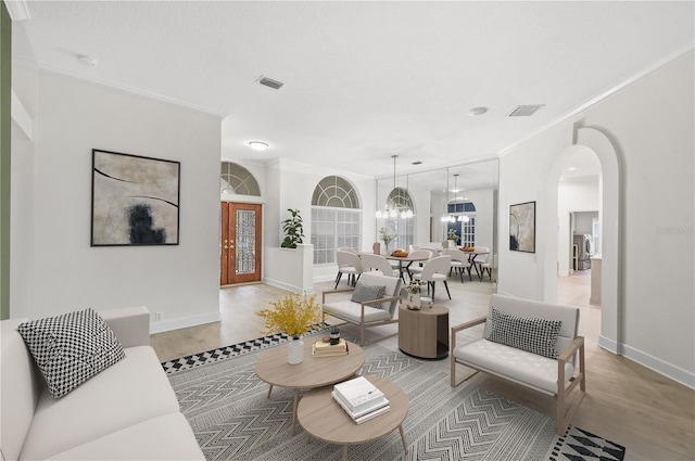 living room featuring visible vents, arched walkways, wood finished floors, and ornamental molding