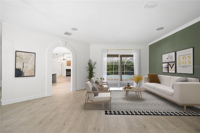 living area with crown molding, visible vents, arched walkways, and wood finished floors