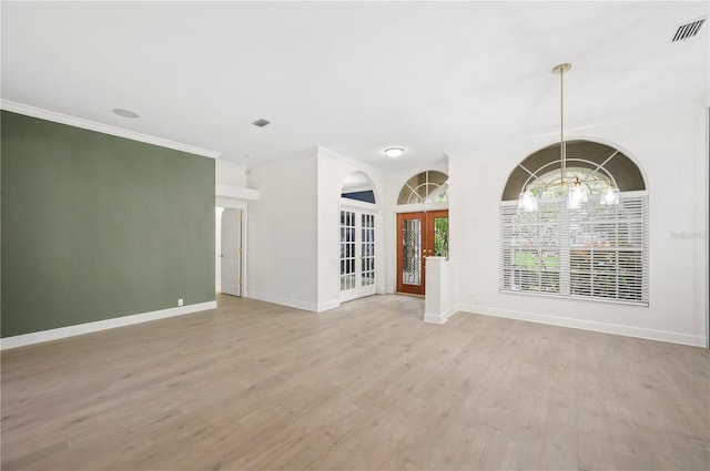 unfurnished room with light wood-style flooring, visible vents, crown molding, and french doors