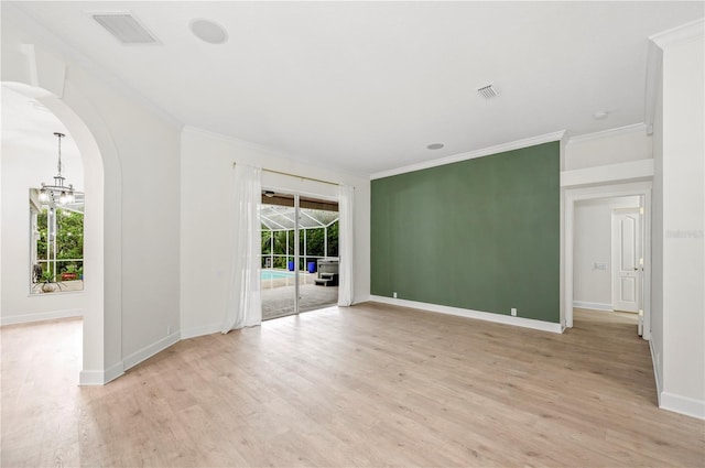 spare room featuring light wood-style flooring, visible vents, arched walkways, and crown molding