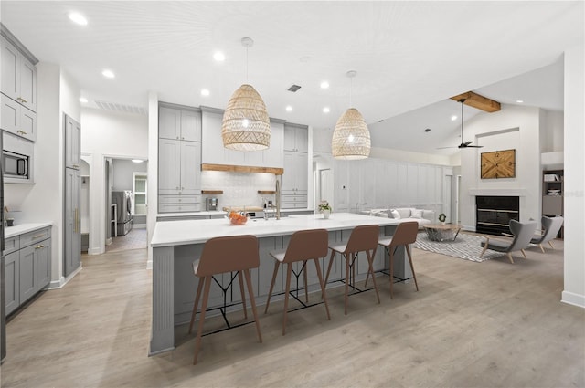 kitchen featuring decorative backsplash, a glass covered fireplace, light wood-style floors, and gray cabinetry