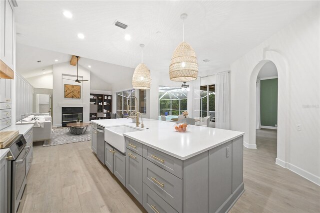 kitchen with visible vents, light wood-style floors, open floor plan, gray cabinets, and a glass covered fireplace