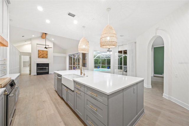 kitchen featuring light wood-style flooring, a sink, visible vents, gray cabinets, and a glass covered fireplace