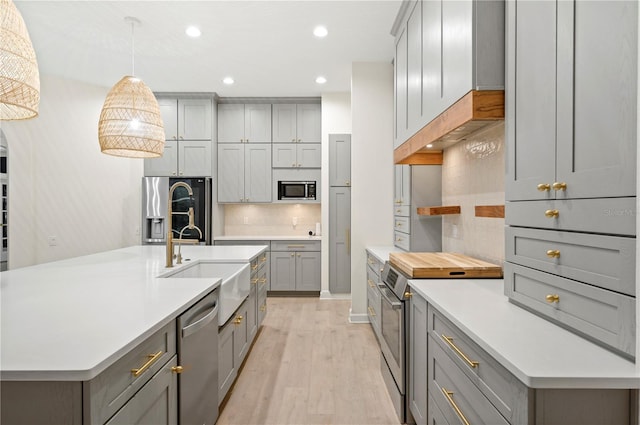 kitchen featuring tasteful backsplash, stainless steel appliances, gray cabinets, and a sink