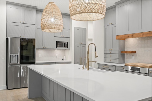 kitchen featuring appliances with stainless steel finishes, gray cabinets, light countertops, and backsplash