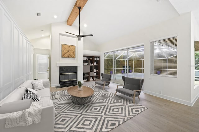 living area featuring a fireplace, wood finished floors, a sunroom, baseboards, and beamed ceiling