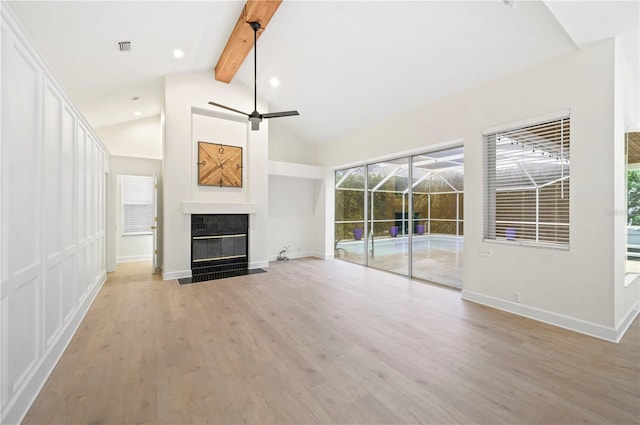 unfurnished living room with a fireplace with flush hearth, a ceiling fan, a sunroom, wood finished floors, and beamed ceiling