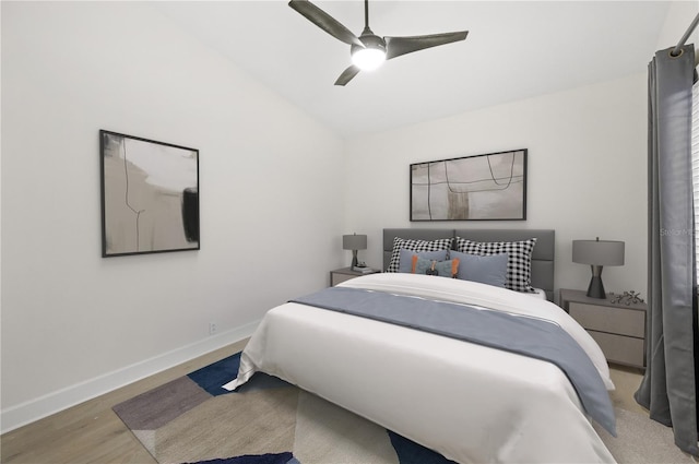 bedroom with lofted ceiling, light wood-style flooring, baseboards, and a ceiling fan