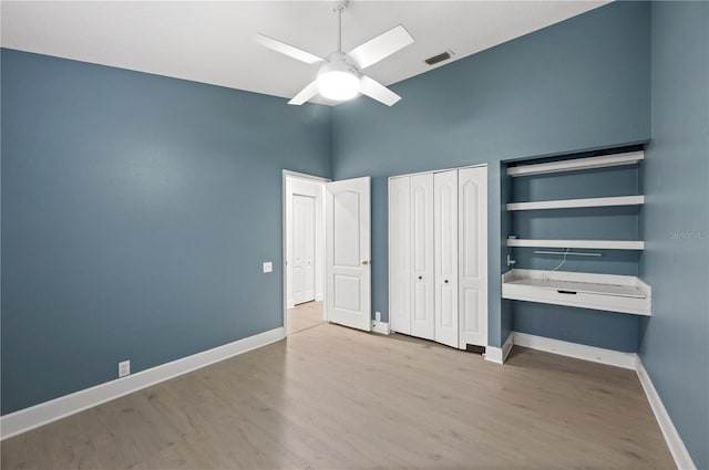 unfurnished bedroom with ceiling fan, wood finished floors, visible vents, baseboards, and a closet