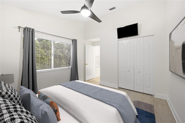 bedroom featuring a ceiling fan, visible vents, baseboards, a closet, and light wood finished floors