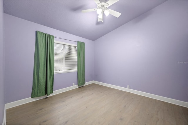 unfurnished room featuring vaulted ceiling, wood finished floors, and baseboards