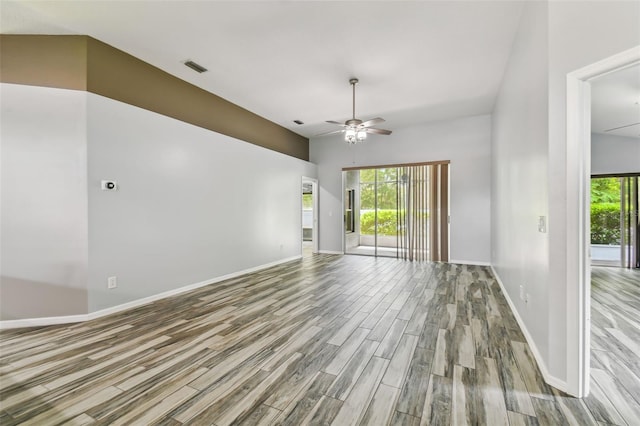 empty room featuring visible vents, wood finished floors, a wealth of natural light, and a ceiling fan