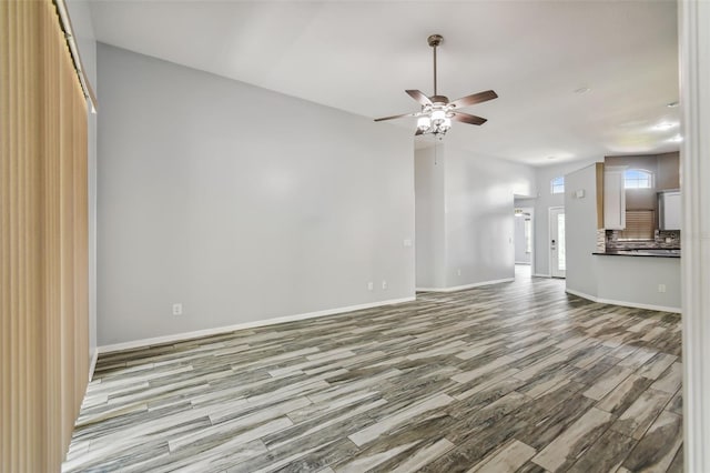 unfurnished living room featuring baseboards, a ceiling fan, and wood finished floors