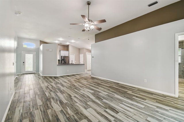 unfurnished living room with ceiling fan, wood finished floors, visible vents, and baseboards