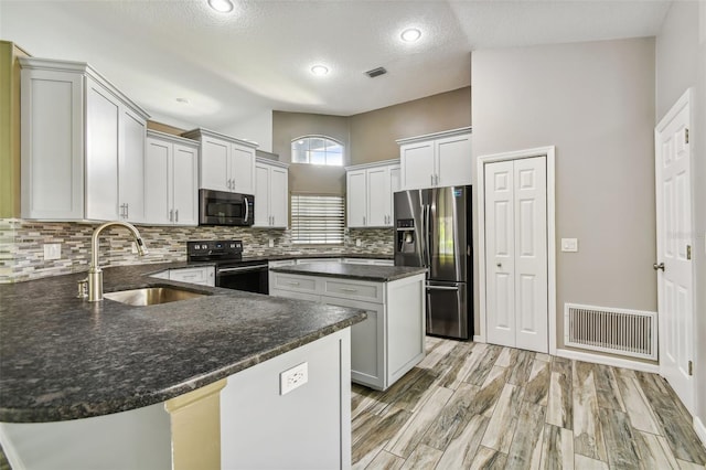 kitchen featuring stainless steel appliances, visible vents, a sink, and a peninsula