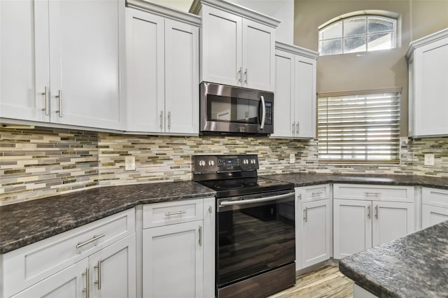 kitchen featuring dark stone countertops, stainless steel microwave, backsplash, and electric stove