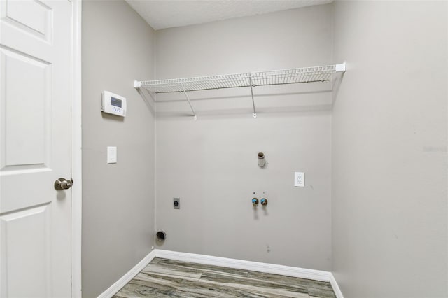 clothes washing area featuring laundry area, baseboards, hookup for a gas dryer, wood finished floors, and hookup for an electric dryer