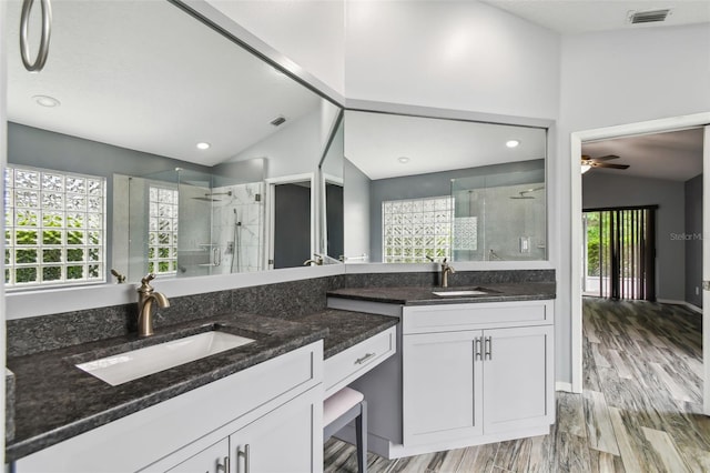 kitchen with dark stone counters, vaulted ceiling, visible vents, and a sink