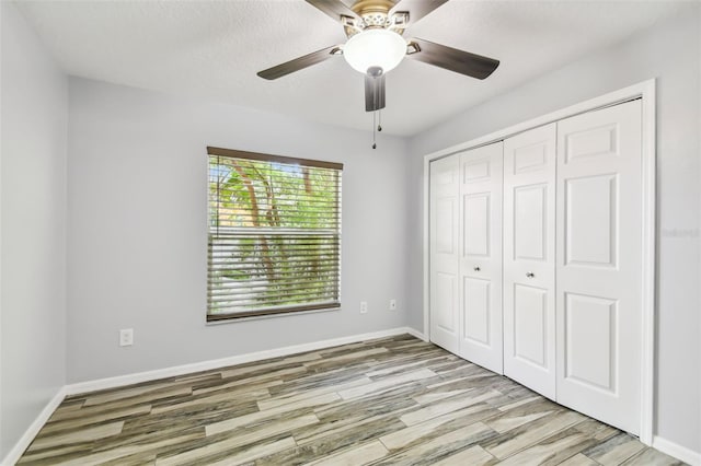 unfurnished bedroom with a closet, wood finished floors, a ceiling fan, and baseboards