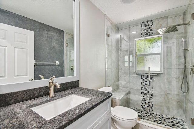 full bathroom with a stall shower, vanity, toilet, and a textured ceiling