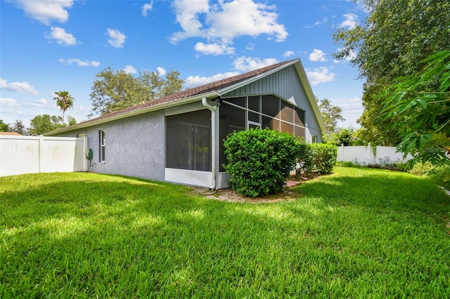 back of house with a sunroom, a fenced backyard, a yard, and stucco siding