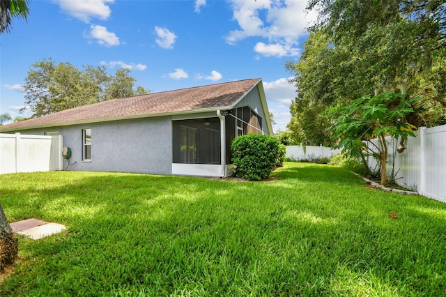 rear view of property featuring a sunroom, a fenced backyard, stucco siding, and a yard