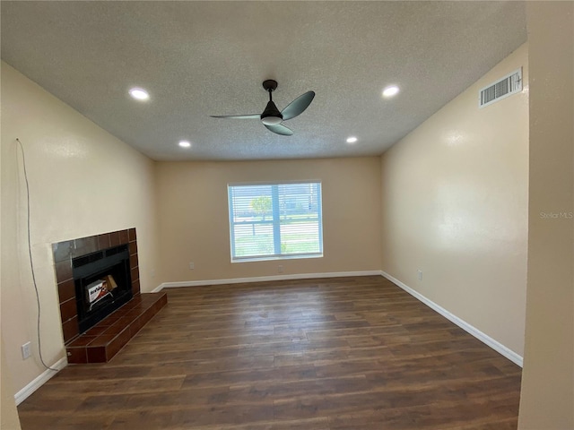 unfurnished living room featuring a textured ceiling, dark wood-style flooring, a fireplace, visible vents, and baseboards