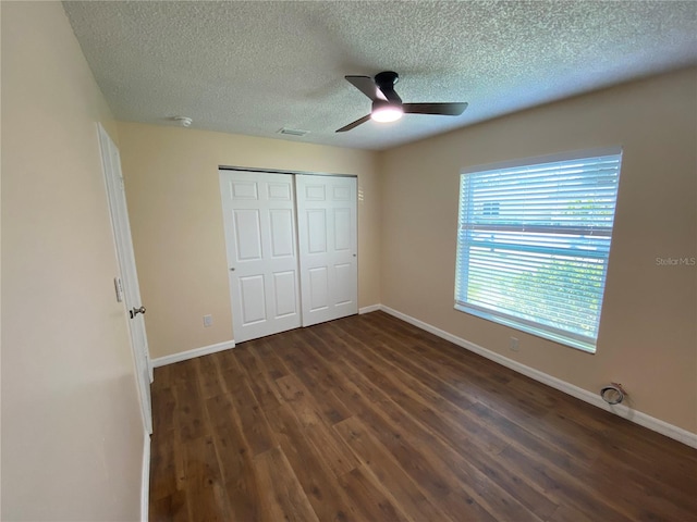 unfurnished bedroom featuring baseboards, a ceiling fan, dark wood-style flooring, a textured ceiling, and a closet