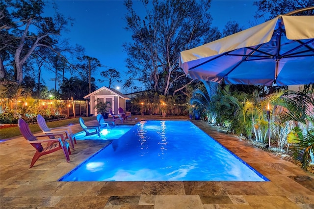 pool at twilight with a fenced in pool, an outbuilding, a patio, fence, and a storage structure