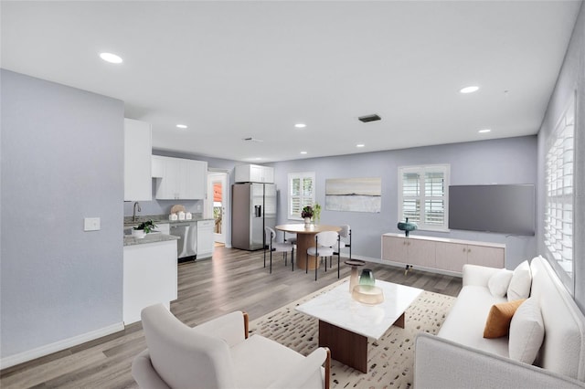 living area with baseboards, light wood-type flooring, and recessed lighting