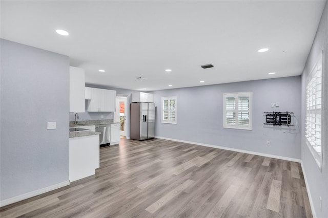 unfurnished living room with recessed lighting, wood finished floors, a sink, visible vents, and baseboards