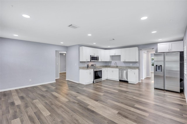 kitchen with appliances with stainless steel finishes, recessed lighting, a sink, and wood finished floors