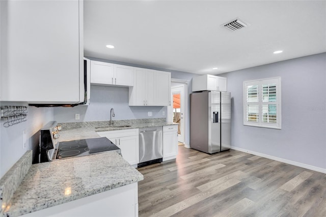 kitchen with light wood finished floors, visible vents, stainless steel appliances, white cabinetry, and a sink