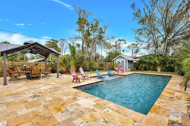 view of pool featuring a patio, a fenced backyard, an outdoor structure, a gazebo, and a storage unit