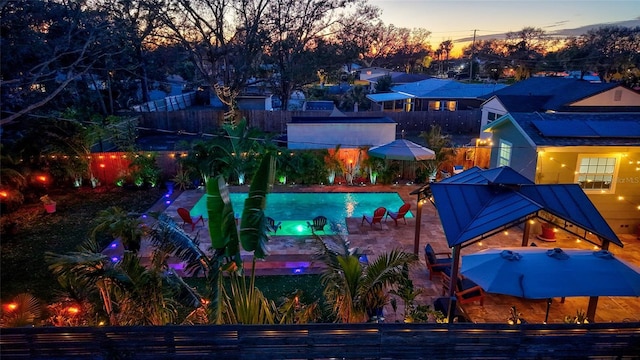 pool at dusk featuring a patio area, fence private yard, and an outdoor pool