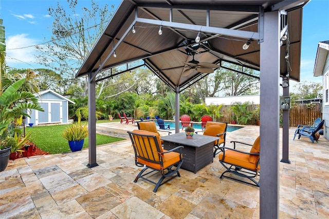 view of patio with a fenced in pool, ceiling fan, fence, an outdoor structure, and a shed