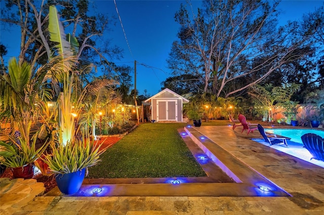 view of yard featuring a fenced in pool, a fenced backyard, an outbuilding, a patio area, and a shed