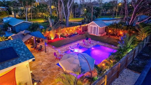 view of pool featuring a storage shed, a fenced backyard, a patio area, and an outdoor structure