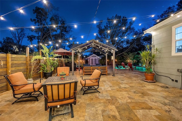 patio at twilight with a fenced backyard, a storage unit, and an outbuilding