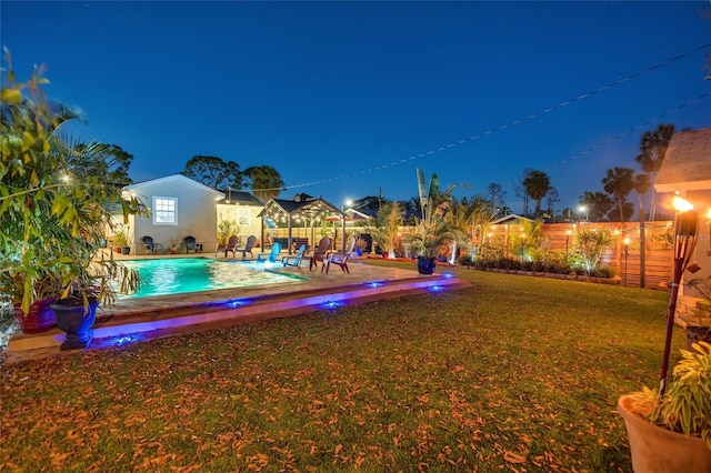 yard at night featuring an outdoor pool, fence, and a patio