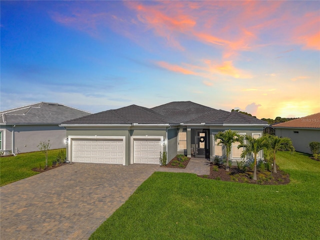 view of front facade with an attached garage, a front lawn, decorative driveway, and stucco siding