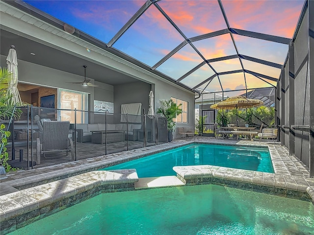 pool at dusk with a ceiling fan, a pool with connected hot tub, a patio area, and outdoor lounge area