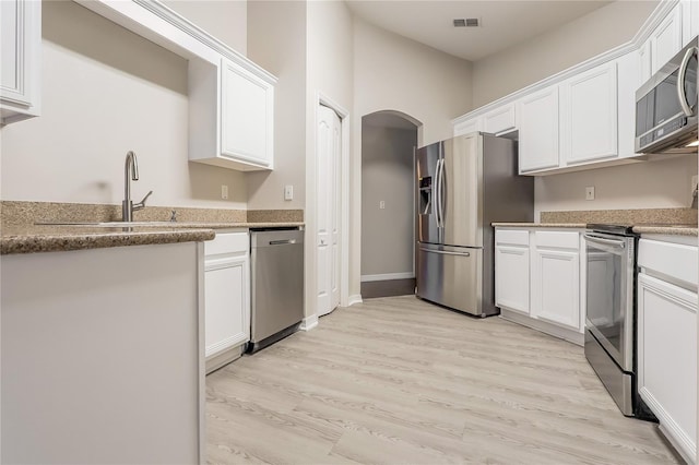 kitchen with visible vents, appliances with stainless steel finishes, white cabinets, a sink, and light wood-type flooring