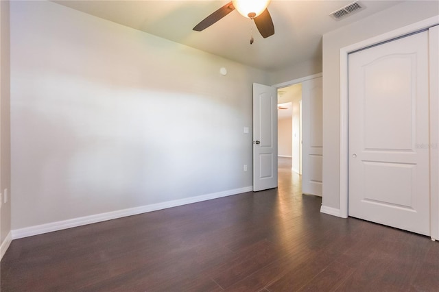 unfurnished bedroom featuring dark wood-style floors, a closet, visible vents, a ceiling fan, and baseboards